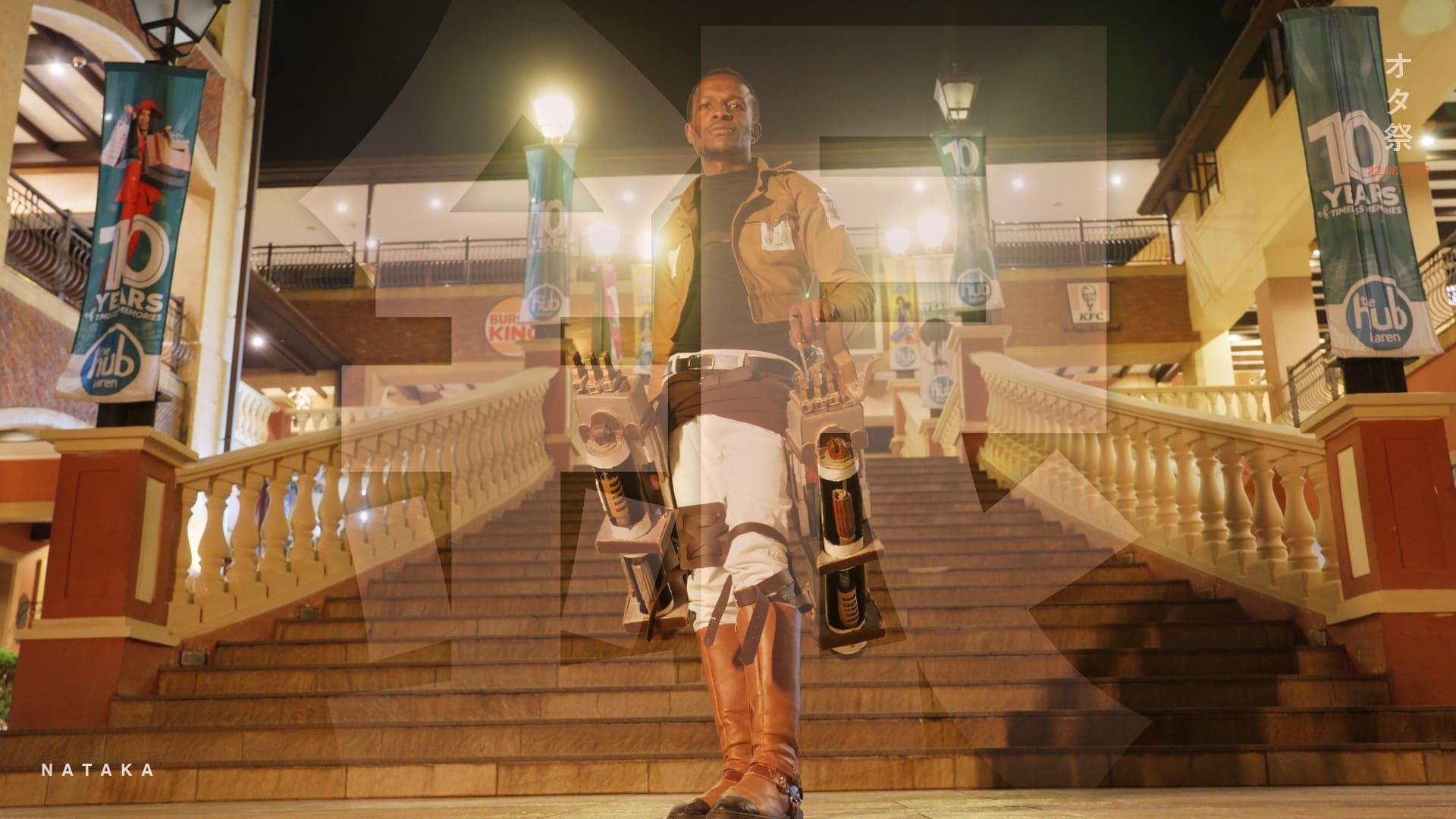 Otamatsuri cosplay in Nairobi: a Kenyan cosplayer in a Survey Corps uniform and handmade ODM gear on a lit staircase at night